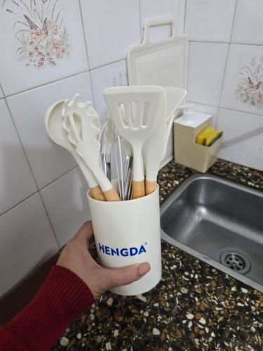 a person is holding a cup filled with utensils at Italia apart departamentos por día con cochera opcional in Corrientes