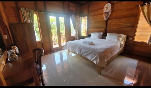 a bedroom with a bed in a wooden room at Nora Cottage Natural in Batununggul
