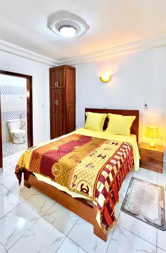 a bedroom with a large bed and a bathroom at BJ House in Douala