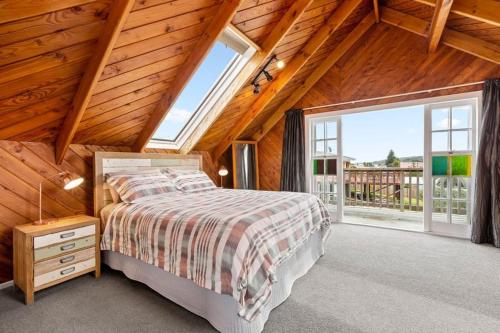 a bedroom with a bed and a large window at Large Bach in Raglan central in Raglan