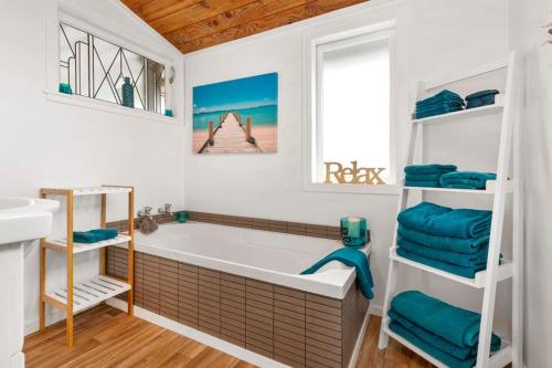 a bathroom with a bath tub and a sink at Large Bach in Raglan central in Raglan