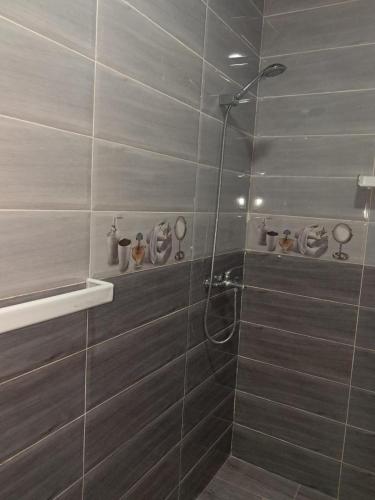 a shower in a bathroom with gray tiles at mdiq in M'diq