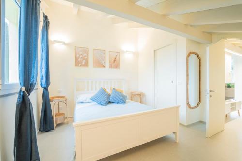 a white bedroom with a bed with blue pillows at Ulivo, Relax a due passi dal mare in San Lazzaro