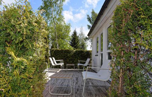 a patio with white chairs and tables and bushes at Gorgeous Home In Ystad in Ystad