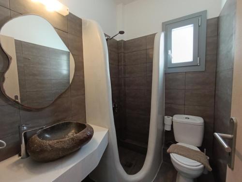 a bathroom with a sink and a toilet and a mirror at Perissa Economy Rooms in Santorini