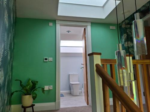 a hallway with green walls and a staircase with a toilet at The Old Saw Mill in Llangunllo