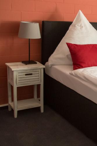 a bed with a red pillow and a table with a lamp at Landhaus Elbeflair bei Dömitz in Lenzerwische