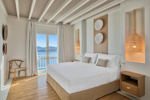 a bedroom with a large white bed and a balcony at Santa Marina, A Luxury Collection Resort, Mykonos in Ornos