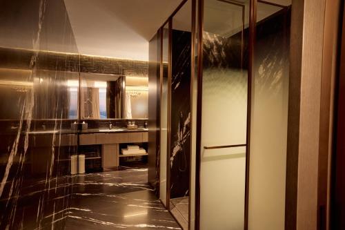 a bathroom with a mirror and a sink and a refrigerator at Steigenberger Phnom Penh in Phnom Penh
