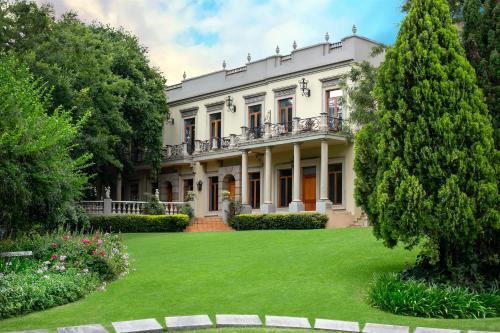 una grande casa con un cortile verde di Fairlawns Boutique Hotel & Spa a Johannesburg
