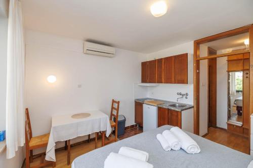 a kitchen with two beds and a table and a kitchen with a sink at Maja Apartments Malinska in Malinska