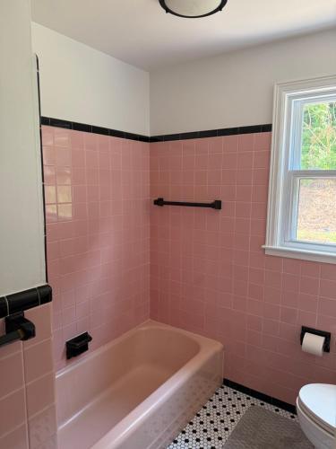 a pink bathroom with a tub and a toilet at Boho room in house in New Haven