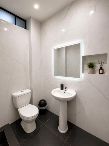 a white bathroom with a toilet and a sink at Libertad Grand Hotel in Ayacucho