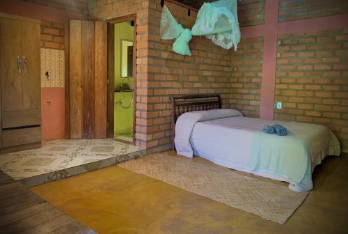 a bedroom with a bed and a brick wall at Kumaru Pousada e Restaurante in Palmeiras