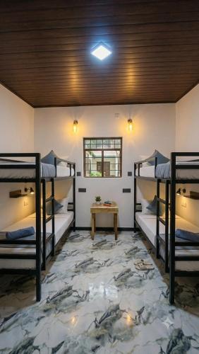 a room with three bunk beds and a table at Ceylora Resort in Sigiriya