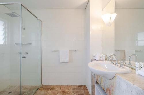 a white bathroom with a sink and a shower at Balboa Apartments in Port Douglas