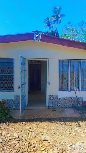 a small white house with a gate and a door at Nasau Holiday Apartment in Sigatoka