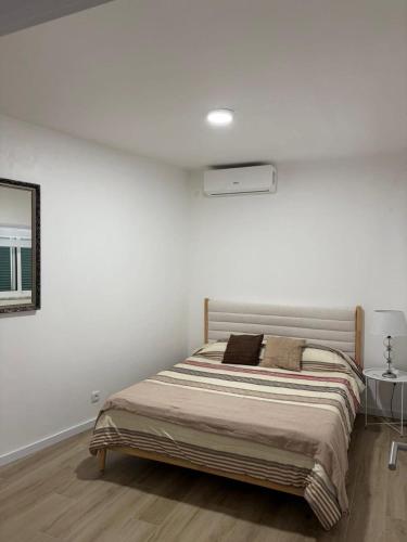 a white bedroom with a bed and a mirror at Casa Brumar Beach and Downtown on Foot in Praia da Vitória