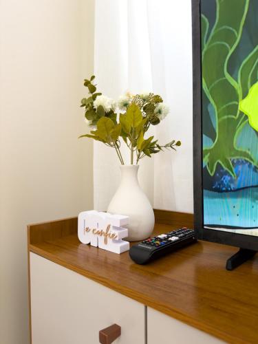 a table with a tv and a vase with flowers at Casa 01 - Completa e moderna 5 minutos do centro in Alta Floresta