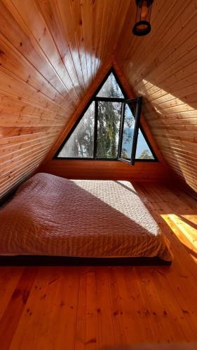 a bed in a room with a window in a cabin at Magnolia Cottage in Ts'ikhisdziri
