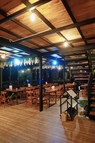 a restaurant with wooden tables and chairs and lights at CYB Merbabu Resort & Cafe in Kembang