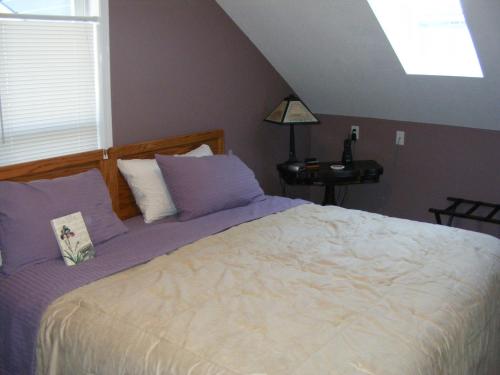 ein Schlafzimmer mit einem Bett mit violetter Bettwäsche und einem Fenster in der Unterkunft Hummingbird Guesthouse in Port Alberni