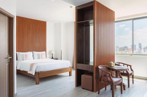 a bedroom with a bed and a desk and a window at The ONRA Hotel in Phnom Penh