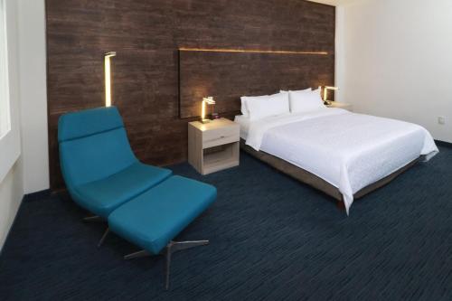 a bedroom with a bed and a blue chair at Holiday Inn Express San Luis Potosí by IHG in San Luis Potosí