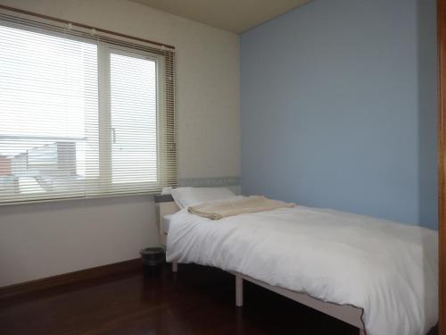 a bedroom with a white bed and a window at 愛灯-ｉｔｏ- in Kami-furano