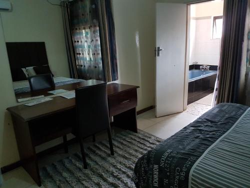 a bedroom with a desk with a computer and a bed at Rugems Executive Lodge in Lusaka