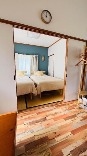 a mirror in a room with two beds and a clock at IWAKI Stay KAKUREGI in Hirosaki