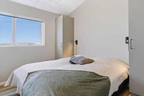 a white bedroom with a bed with a window at 839-Harboore-Strandvaenget-6 in Harboør