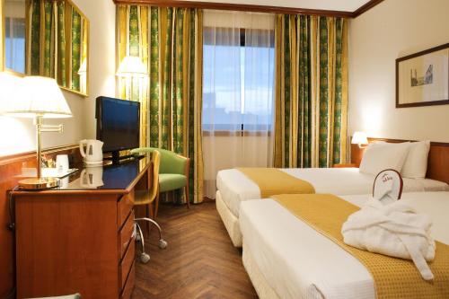 a hotel room with two beds and a desk at Hotel Catullo in San Martino Buon Albergo