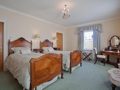 a bedroom with two beds and a desk and a mirror at West Longridge Manor B&B in Berwick-Upon-Tweed