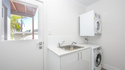 a white laundry room with a sink and a washing machine at Moby Dick Waterfront Resort Motel in Yamba