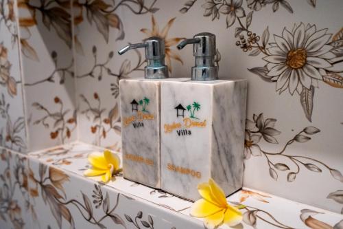 two faucets on top of a counter with flowers at Puri Mayapada Nusa Dua Bali in Nusa Dua