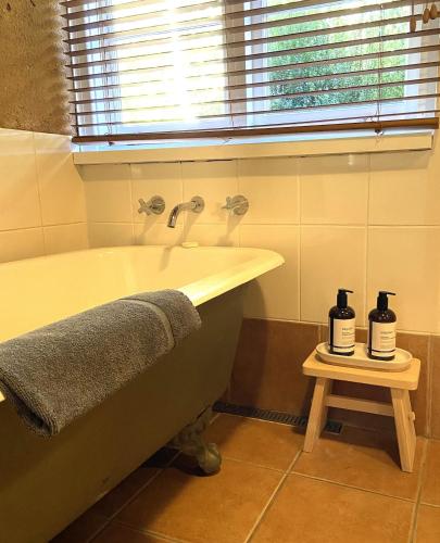 a bathroom with a bath tub with two bottles on a table at Eucalyptus House in Pemberton