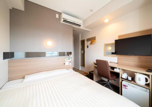 a hotel room with a bed and a desk and a tv at Super Hotel Totsuka Eki Higashiguchi in Yokohama