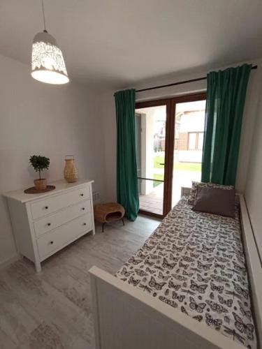 a bedroom with a bed and a dresser and green curtains at Apartament łeba in Żarnowska