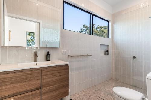 a bathroom with a toilet and a sink and a window at Fernleigh Stay in Fernleigh