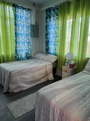 two beds in a bedroom with green curtains at Golden Isles Paradise in Port-of-Spain