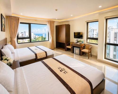 a hotel room with two beds and a desk at Thăng long II Hotel flc sầm sơn Thanh Hóa in Sầm Sơn