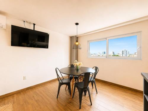 a dining room with a table and chairs and a tv at Modernos departamentos tipo LOFT a dos calles del estadio in Boca del Río