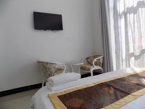 a bedroom with a bed and two chairs and a flat screen tv at Remmings Hotel Kampala in Kampala