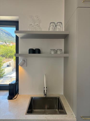 a kitchen with a sink and shelves with a window at Casa Bol Old Town in Bol