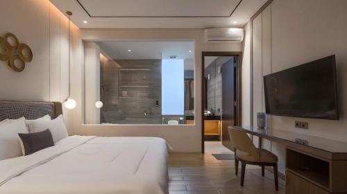 a bedroom with a bed and a television and a bathroom at Alcola Boutique Villa - Caspia Unit in Tlekung
