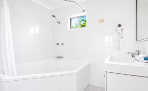 a white bathroom with a tub and a sink at Motel Ingham in Ingham