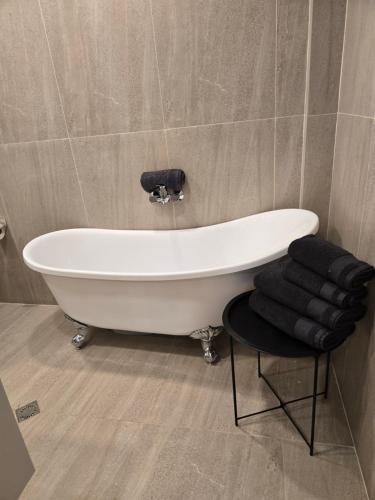 a white bath tub in a bathroom with a stool at Tempo apartments in Pazardzhik