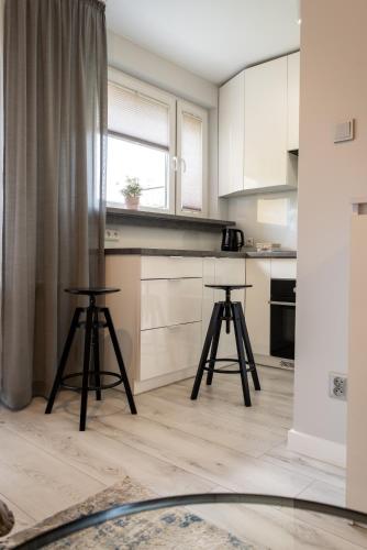 a kitchen with two stools in front of a counter at Apartament Targowa 9A41 in Uniejow