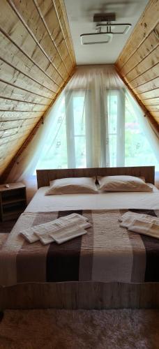 a large bed in a room with a large window at Cabana A frame Nămăiești in Nămăeşti